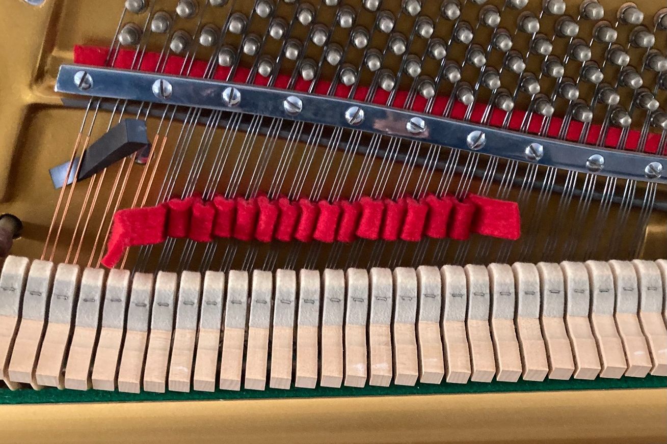bande de feutre dans les corde d un  piano avant de l accorder